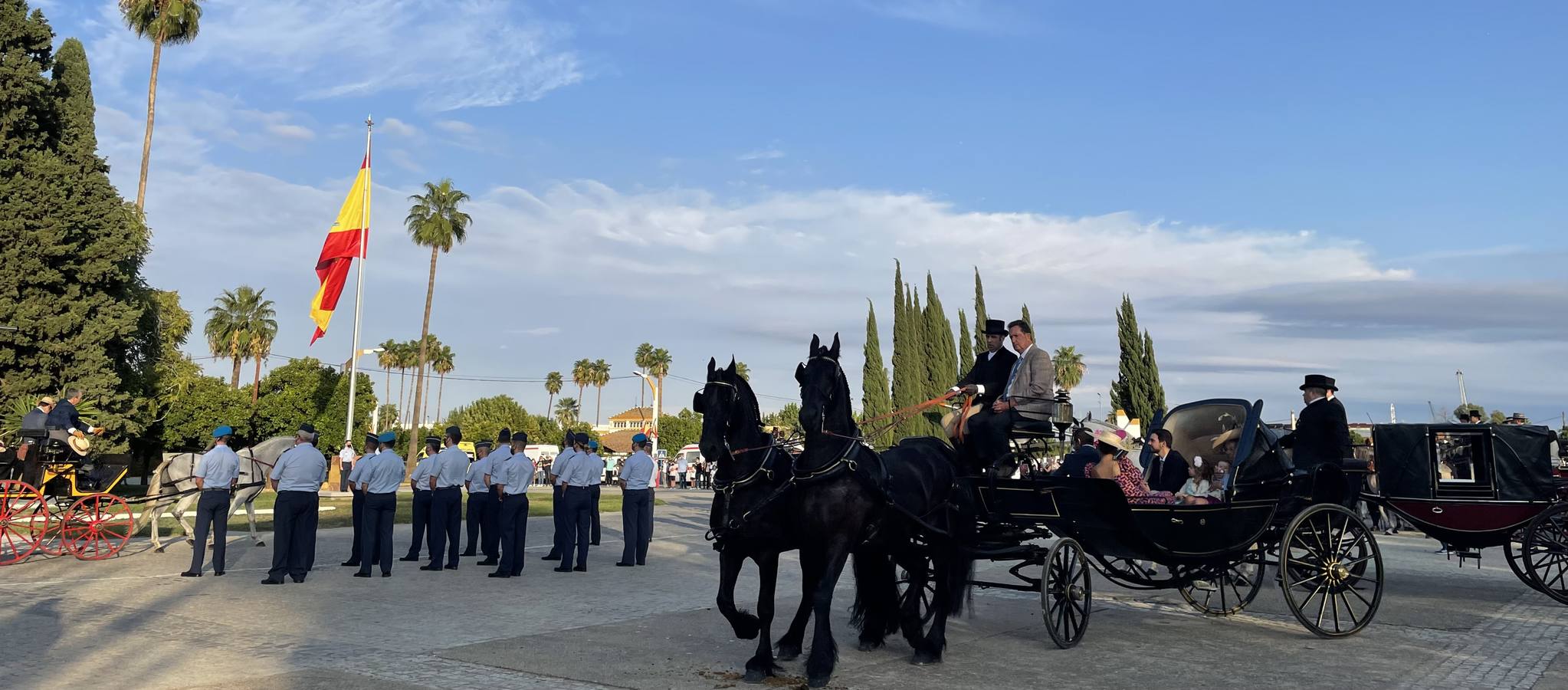 Izado de bandera en Tablada, con los carruajes participantes en el primer paseo por la ciudad.