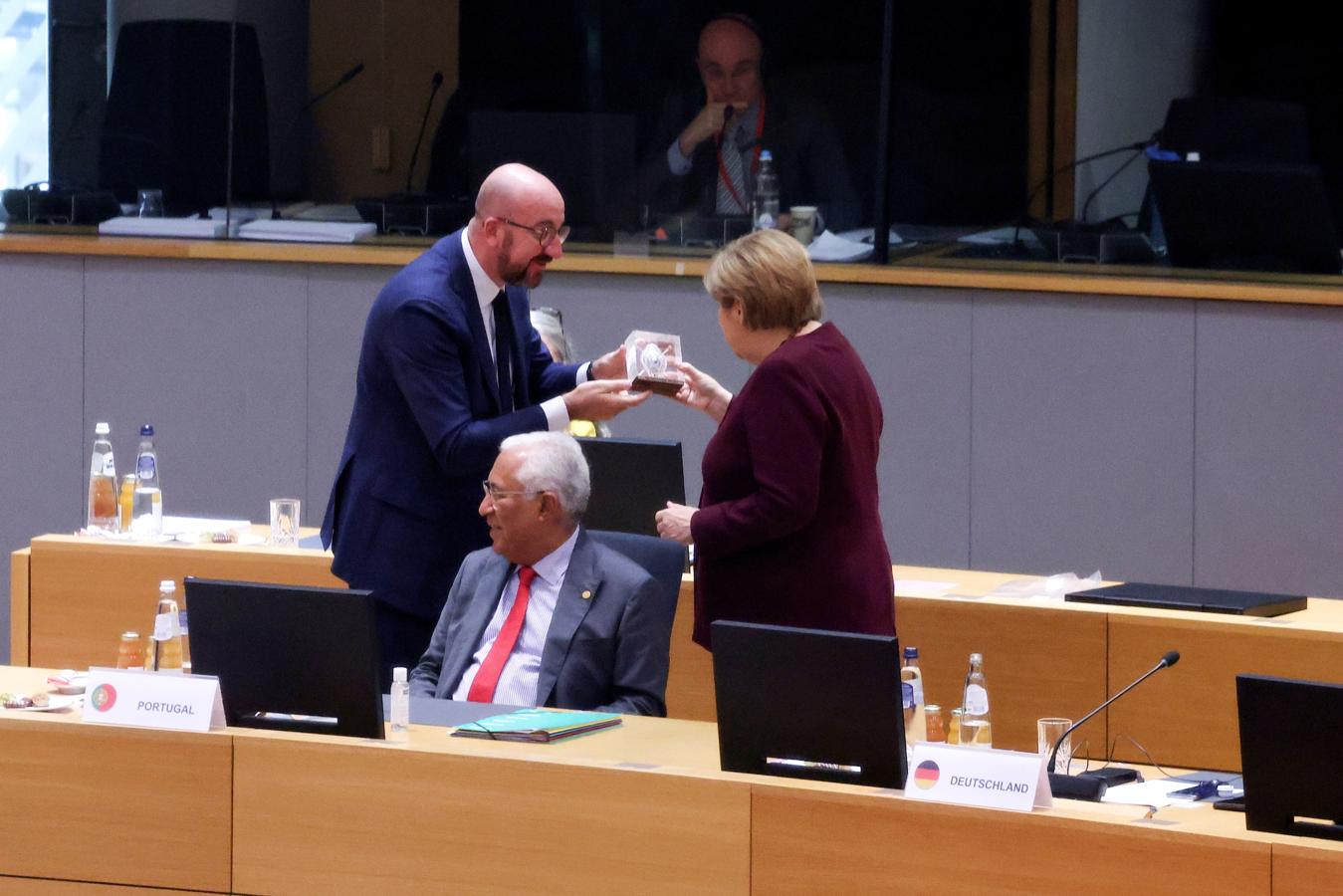 El presidente del Consejo Europeo, Charles Michel (i), entrega un regalo a la canciller alemana, Angela Merkel (d). 