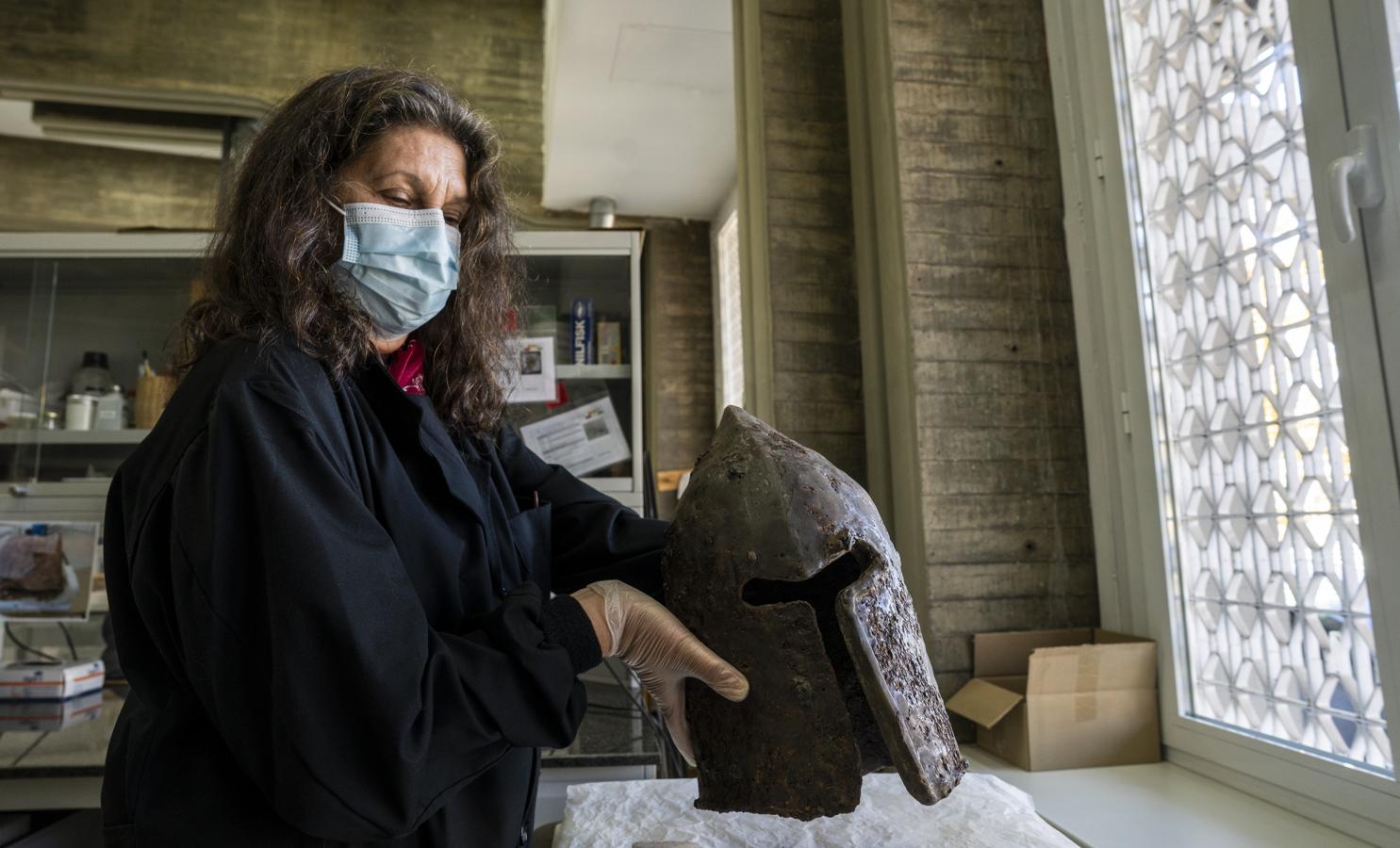 Emma García, restauradora de metales, con uno de los cascos hallados en el castillo de Monreal de Ariza que está siendo restaurado. 