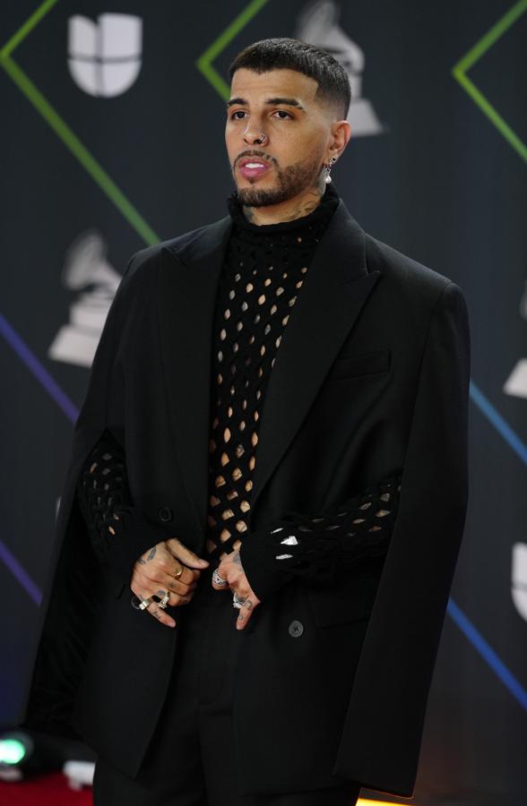 Rauw Alejandro - Alfombra roja de los Grammy Latinos 2021. Lució un total look de Valentino compuesto por un traje de chaqueta negro con mangas capa y un jersey de punto troquelado que dejaba al descubierto el pecho.