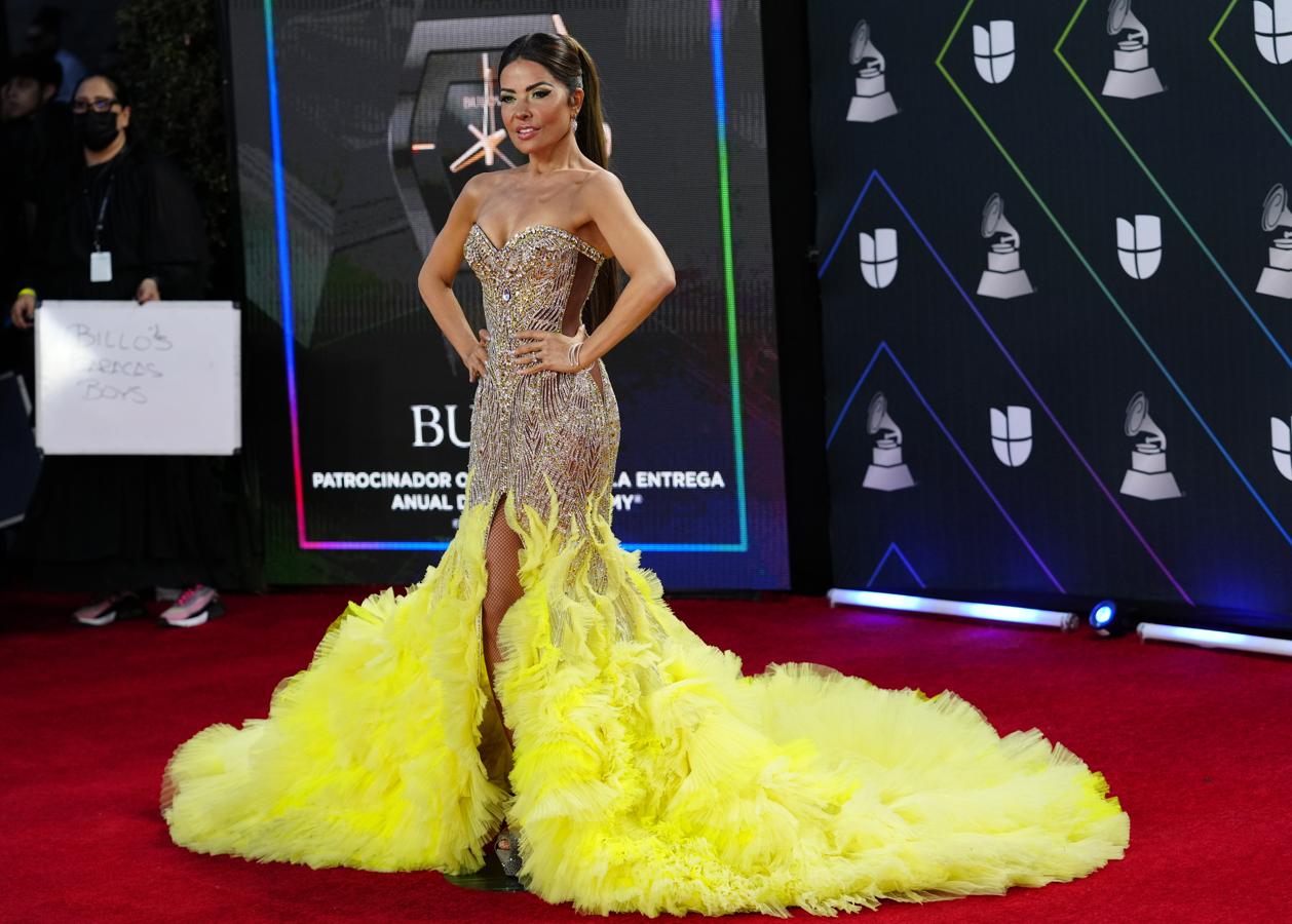 Gloria Trevi, en la alfombra roja de los Grammy Latinos 2021. Con vestido de pailletes de escote palabra de honor con una llamativa cola amarilla.