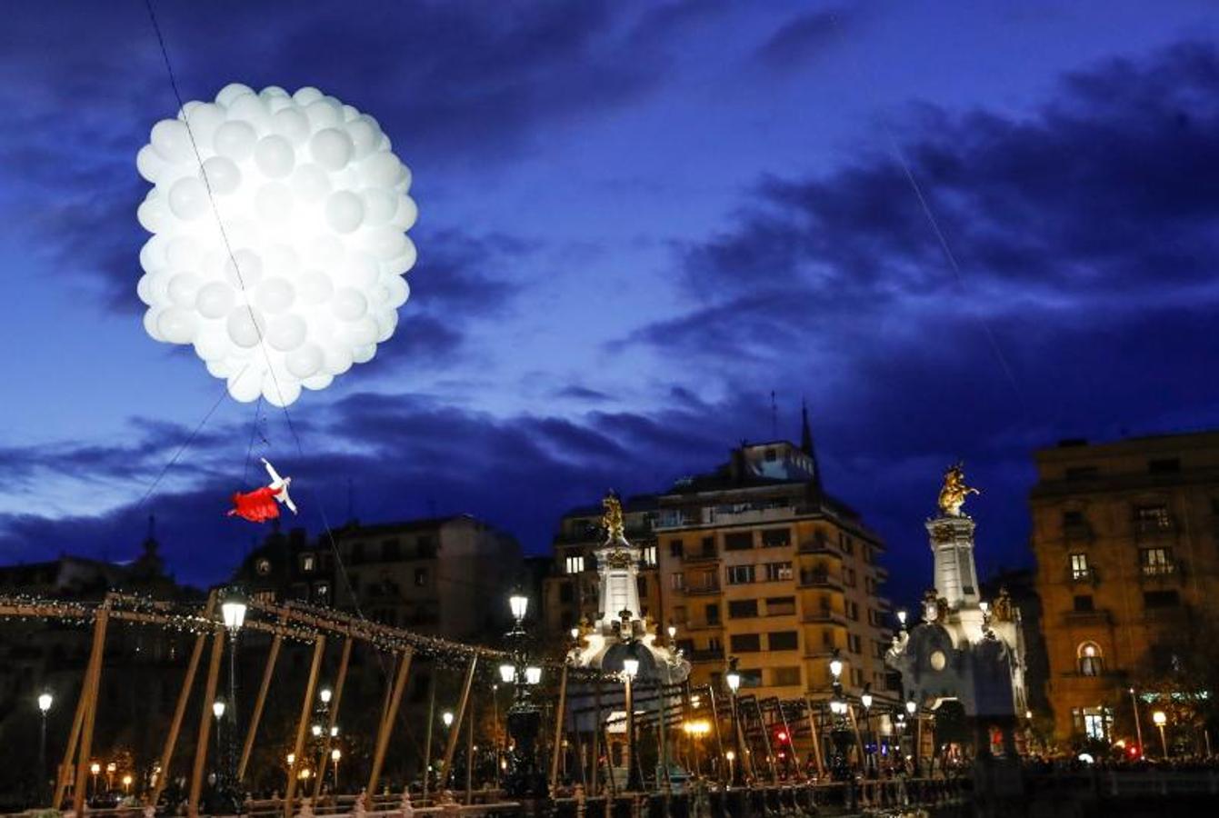 Una bailarina sobrevuela el río Urumea suspendida por globos de helio durante la ceremonia de encendido de las luces navideñas e inauguración del mercado de Navidad este viernes en San Sebastián. 