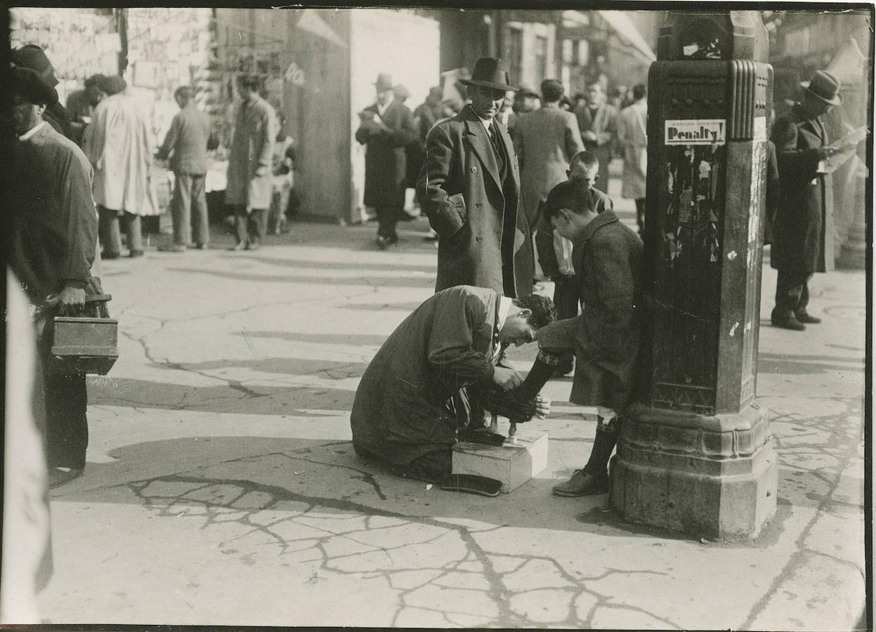 Un limpiabotas le saca brillo a los zapatos de un niño (1933). 