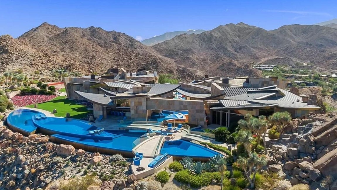 La mansión más excéntrica de Palm Desert de 42 millones. La propiedad se encuentra situada estratégicamente en la cima de una colina y se integra en la naturaleza de una forma muy natural a pesar de sus formas sinuosas que crean un contraste con el entorno. Ha sido creada por Guy Dreier, uno de los diseñadores más afamados de California, y ha recibido múltiples premios, como el otorgado por la revista Robb Report como ‘Vivienda del Año’.