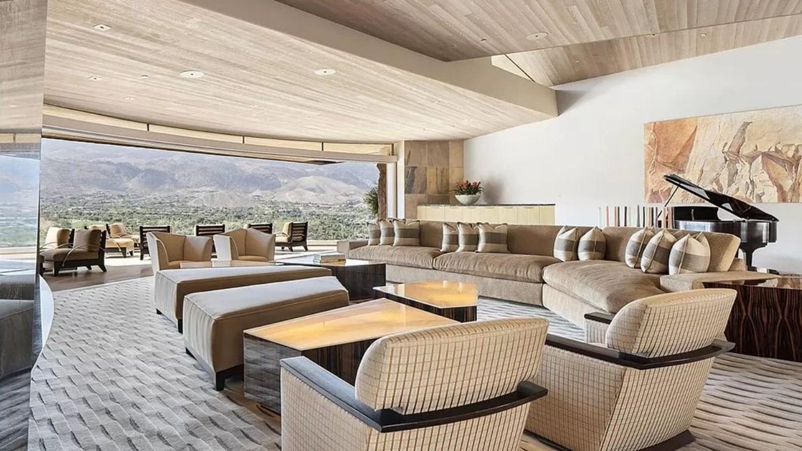 La mansión más excéntrica de Palm Desert de 42 millones. La sala de estar principal posee una decoración vanguardista basada en los contrastes y el foco de atención se encuentra en la enorme chimenea revestida de titanio y un techo de paneles de madera ondulantes.