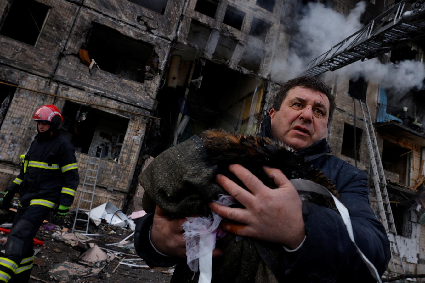 Un hombre sostiene a su gato después de huir de su edificio bombardeado. 