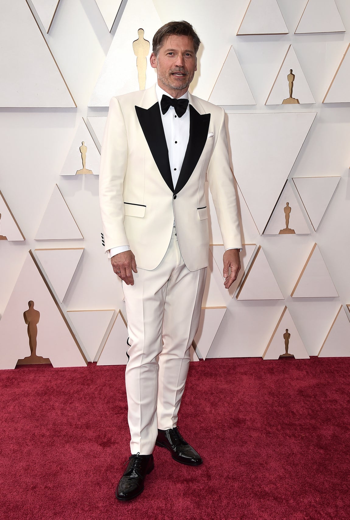 Nikolaj Coster-Waldau- Los mejor vestidos de los Oscar 2022. De blanco y con detalles negros, el esmoquin del actor está firmado por Dolce &amp; Gabbana.