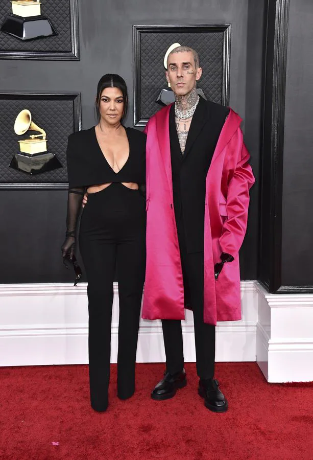 Kourtney Kardashian y Travis Barker - Alfombra roja de los Grammy 2022. El negro fue su elección, ella con un mono con aberturas asimétricas en los costados de la firma Gushnie et Ocsh y él con un traje de Givenchy al que añadió un abrigo fucsia de satén.