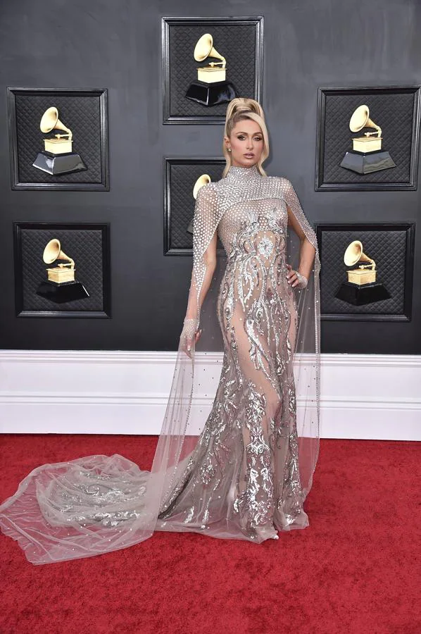Paris Hilton - Alfombra roja de los Grammy 2022. Hizo de las transparencias y las lentejuelas su eleección con un diseño plateado con una gran capa de Atelier Zuhra.