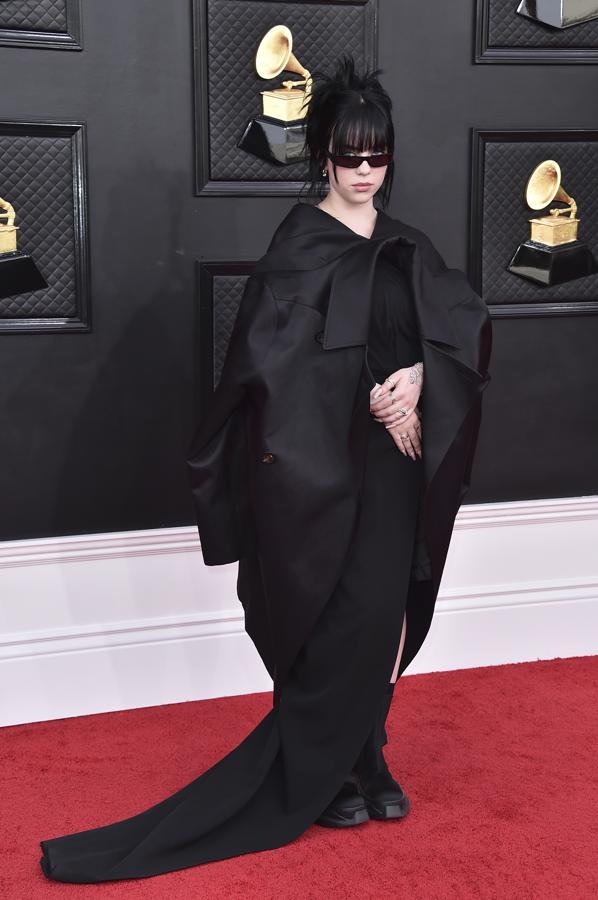 Billie Eilish - Alfombra roja de los Grammy 2022. Como suele ser habitual en sus estilismos, lució un diseño oversize de color negro firmado por Rick Owens que simulaba una blazer deconstruida y que remató con unos botines negros.