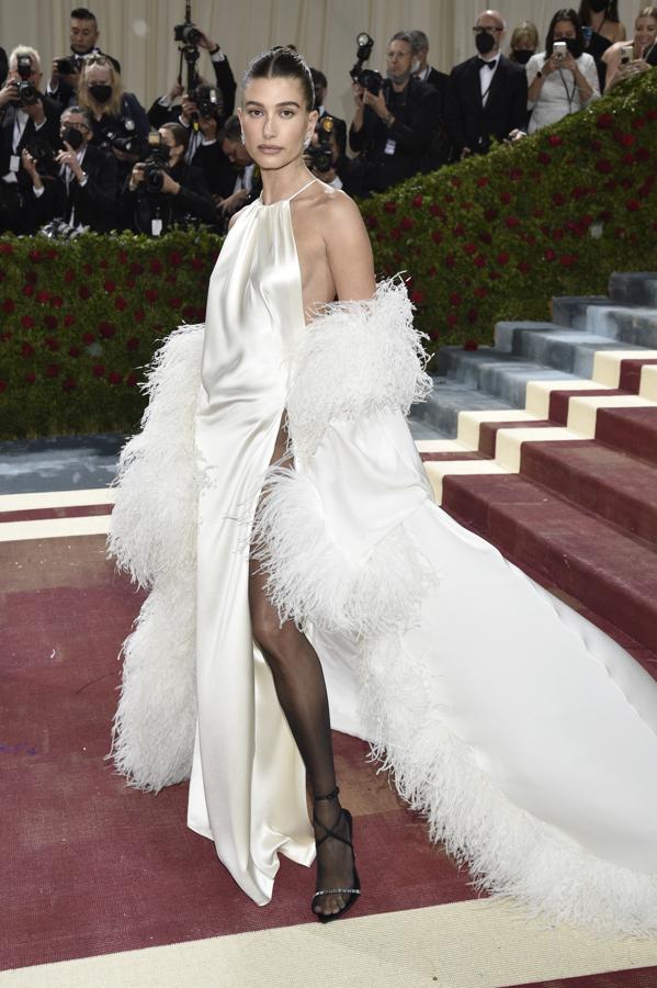 Hailey Bieber - Alfombra roja de la Gala MET 2022. Defendió a la perfección este vestido asimétrico de satén con plumas y larga cola inspirado en los años veinte y firmado por Saint Laurent.