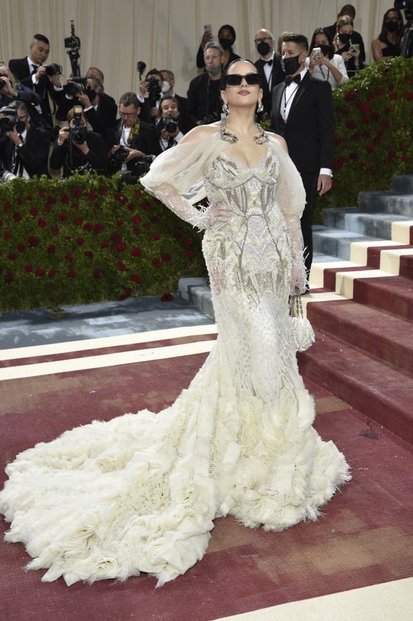 Rosalía - Alfombra roja de la Gala MET 2022. La cantante eligió un diseño en blanco roto de Givenchy compuesto por un cuerpo encorsetado de encaje con lentejuelas y transparencias y una larga cola con plumas.