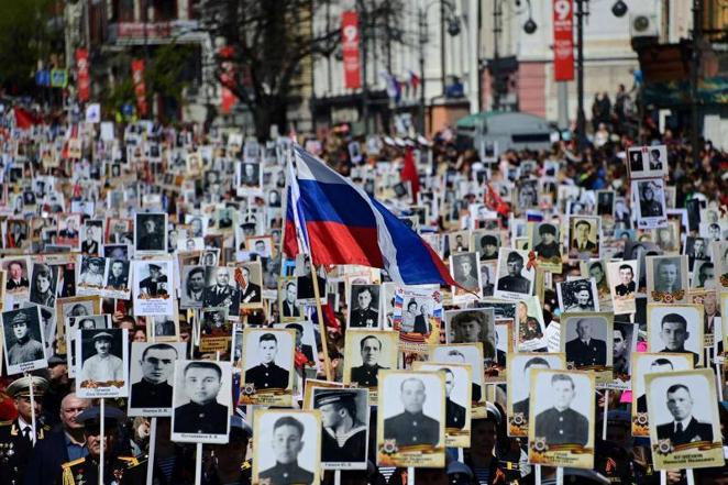 Participantes en el desfile portan fotos de sus familiares caídos en la II Guerra Mundial. 