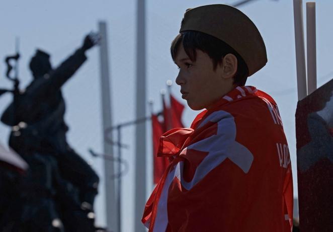 Un niño envuelto con una bandera soviética observa los desfiles del Día de la Victoria en Vladivostok. 