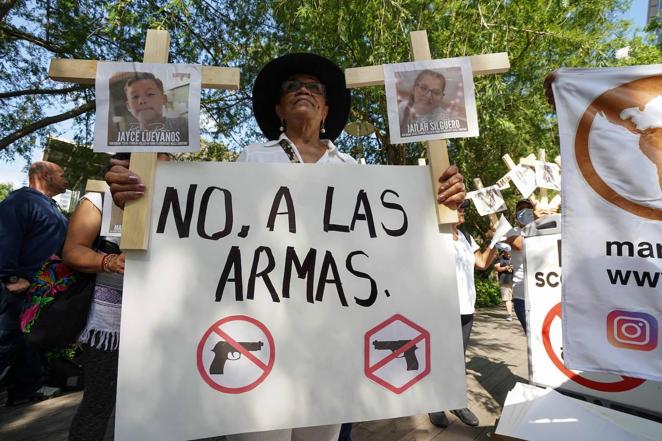 Una mujer sostiene una pancarta donde se lee «No a las armas», junto a las fotografías de dos de los niños que murieron en Uvalde, a las puertas de la Convención Nacional del Rifle que se celebra estos días en Houston (Texas).