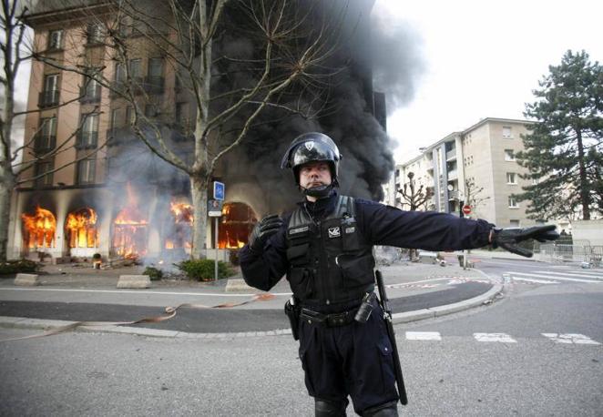 4 de abril de 2009. Un policía francés corta el tráfico junto al Hotel Ibis que arde en un incendio causado por manifestantes durante una manifestación de activistas contrarios a la OTAN en Estrasburgo. Varios colectivos anti OTAN se enfrentaron a la policía mientras los 28 miembros de la organización internacionales celebraban una cumbre y el sesenta aniversario de la Alianza.. 