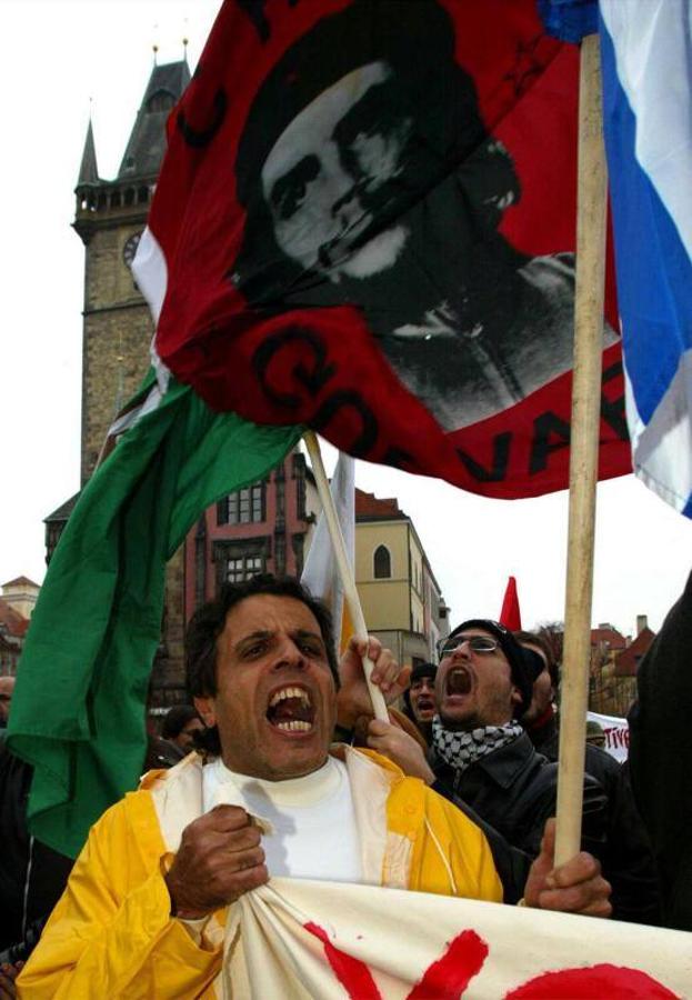 20 de noviembre de 2002. Unos manifestantes gritan durante una protesta contra la OTAN en Praga. El entonces presidente estadounidense, George W. Bush, había anunciado que llamaría a los aliados de la OTAN para ayudarles a desarmar a Saddam Hussein si el líder iraquí se negaba a renunciar al arsenal mortal que Washington creíaque tenía ocultado.. 