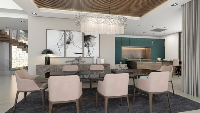 Una villa de lujo frente al mar en Jávea. La zona de comedor, cuya decoración está marcada por una gran lámpara de cristal, ofrece una gran mesa con capacidad para ocho personas y se comunica directamente con la cocina.