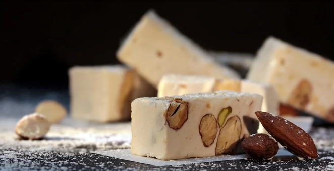 Turrón de almendras. El turrón de almendras tiene menos calorías que el de chocolate, es decir, unas 516 calorías. Aporta 29,3 gramos de grasas, de las que 2,4 gramos son saturadas. Además, 46 gramos son hidratos de carbono, todos ellos azúcares.