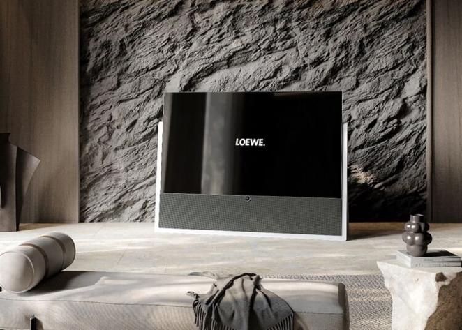 Televisor Loewe iconic. Este televisor de Loewe muestra una elegante tonalidad gris grafito y una base que es un sistema único de alta calidad que ha sido fabricada con Syno-Stone, material mineral sólido y duradero con una superficie no porosa extremadamente higiénica. Disponible en 55 y 65 pulgadas, este diseño ofrece una calidad de imagen perfecta gracias al empleo de paneles OLED 4K de última generación y alta resolución, así como a la calibración individual. Su compatibilidad con HLG, HDR10 y Dolby Vision les capacita para reproducir imágenes de alto contraste y un impresionante espectro de colores que transportan al espectador a horizontes infinitos. El precio del modelo de 65 pulgadas es de 7.999 euros.