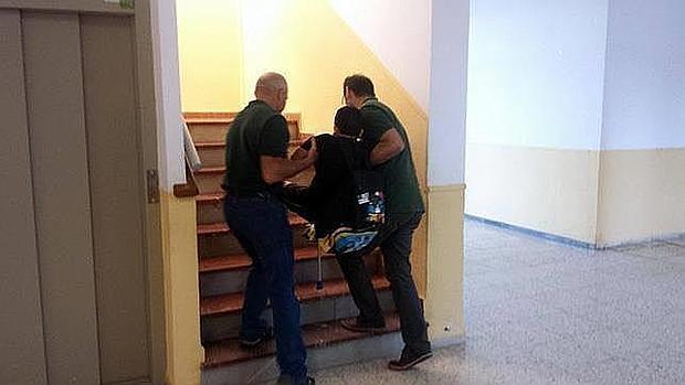 Dos profesores llevan en peso por las escaleras al alumno hasta su aula