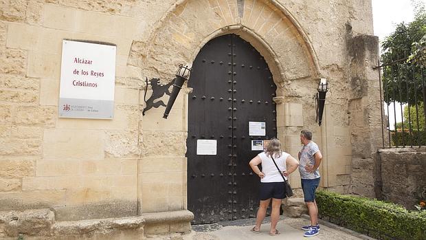 Turistas observan el cartel de cierre del Alcázar en el puente del Pilar