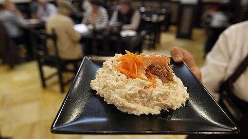 Una camarera lleva un plato de ensaladilla en Bodegas Mezquita