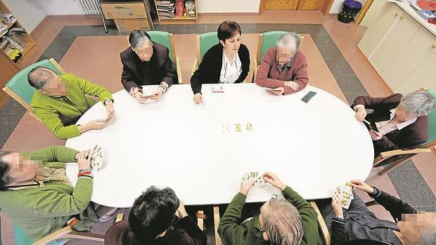 Un grupo de ancianos en torno a una mesa en un centro de mayores