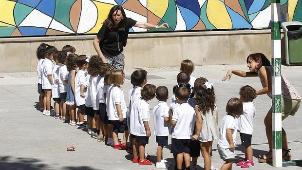 Dos maestras de Infantil en el patio de un colegio en Córdoba con sus alumnos