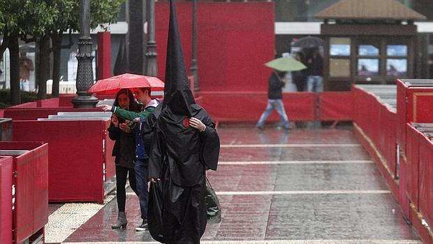 Un nazareno sorprendido por la lluvia en la plaza de las Tendillas