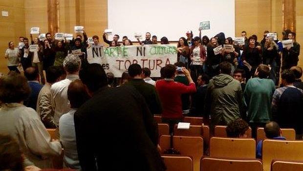 Los antitaurinos en el escenario del salón de actos de Filosofía y Letras tapando a los conferenciantes