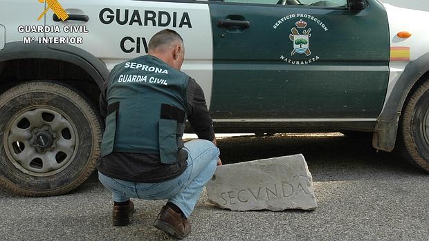 Un agente del Seprona muestra el trozo de lápida funeraria