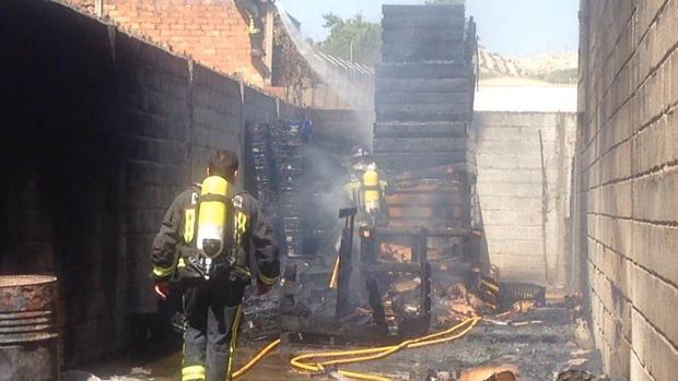 Bomberos en el incendio de una nave de almacenamiento de fruta, en Baena