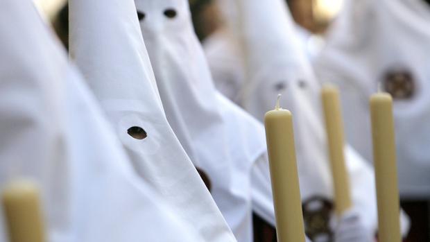 Nazarenos portando cirios durante una procesión en Córdoba