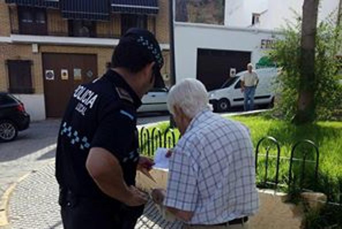 Un agente de la Policía Local de Puente Genil ayuda a un anciano