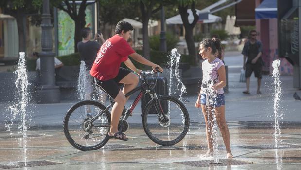 Unos niños juegan en la fuente de la plaza de las Tendillas