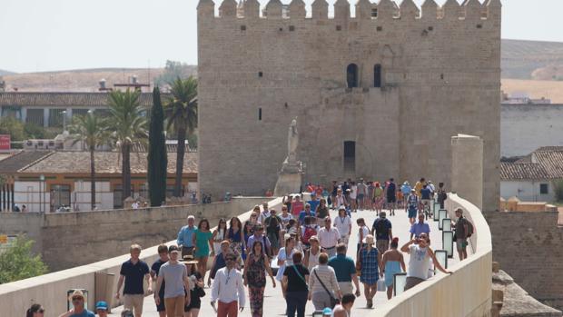 Numerosos turistas pasean por el Puente Romano