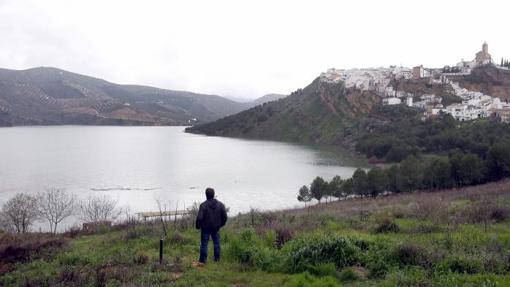 Un vecino contempla las aguas del pantano con Iznájar al fondo