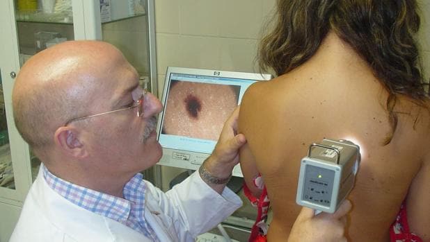 Un dermatólogo examina a una joven en su consulta