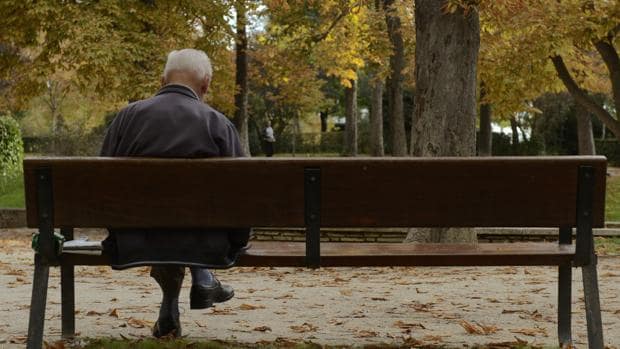 Un hombre de edad avanzada descansa en un banco en el parque