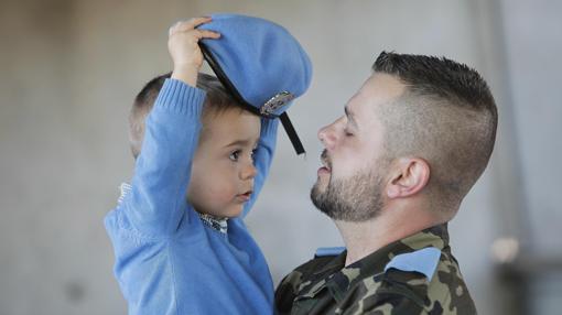 Un niño juega con la boina azul de su padre, que ya está de camino a Líbano