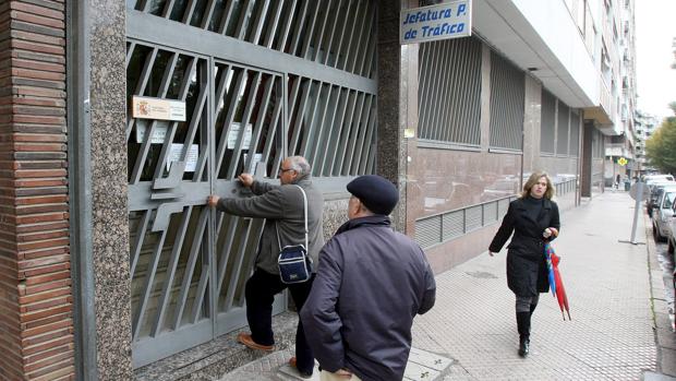 Dos hombres esperan en la puerta de la Jefatura Provincial de Tráfico