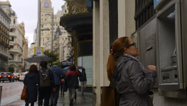 Una usuaria de un banco sacando dinero del cajero