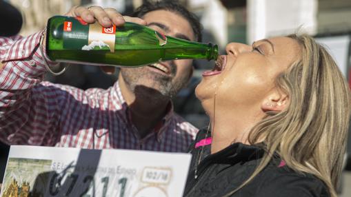 Una mujer bebe cava con el cartel del número 07.211, un cuarto premio en Andújar