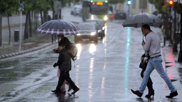 Una familia cruza una calle entre la lluvia