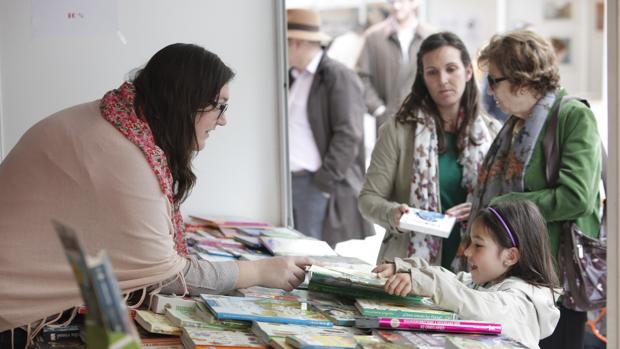 Una niña mira los libros infantiles en un puesto de la Feria del Libro