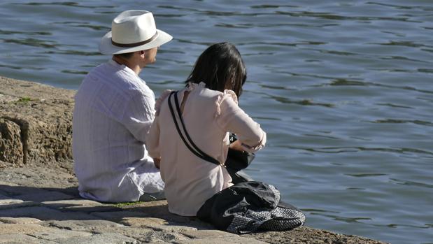 Una pareja se refresca de las altas temperaturas junto al río Guadalquivir