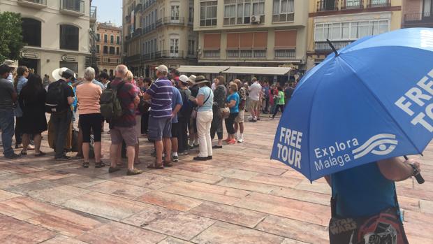 Un grupo de turistas escucha las explicaciones de su guía tras bajar de un crucero en la capital malagueña