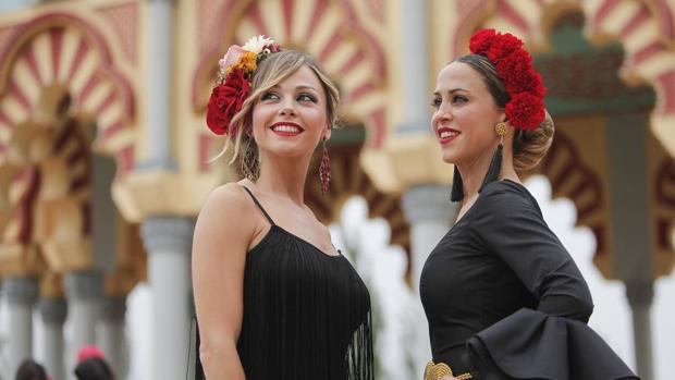 Dos jóvenes vestidas de gitana junto a la Portada de la Feria