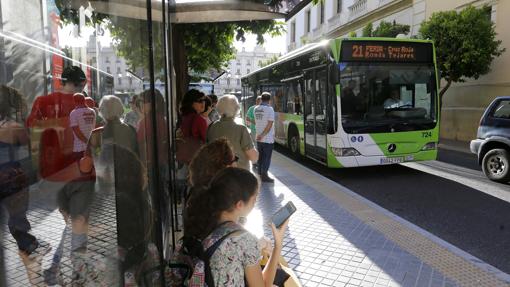 Un grupo de personas espera para acceder a un bus de la Feria